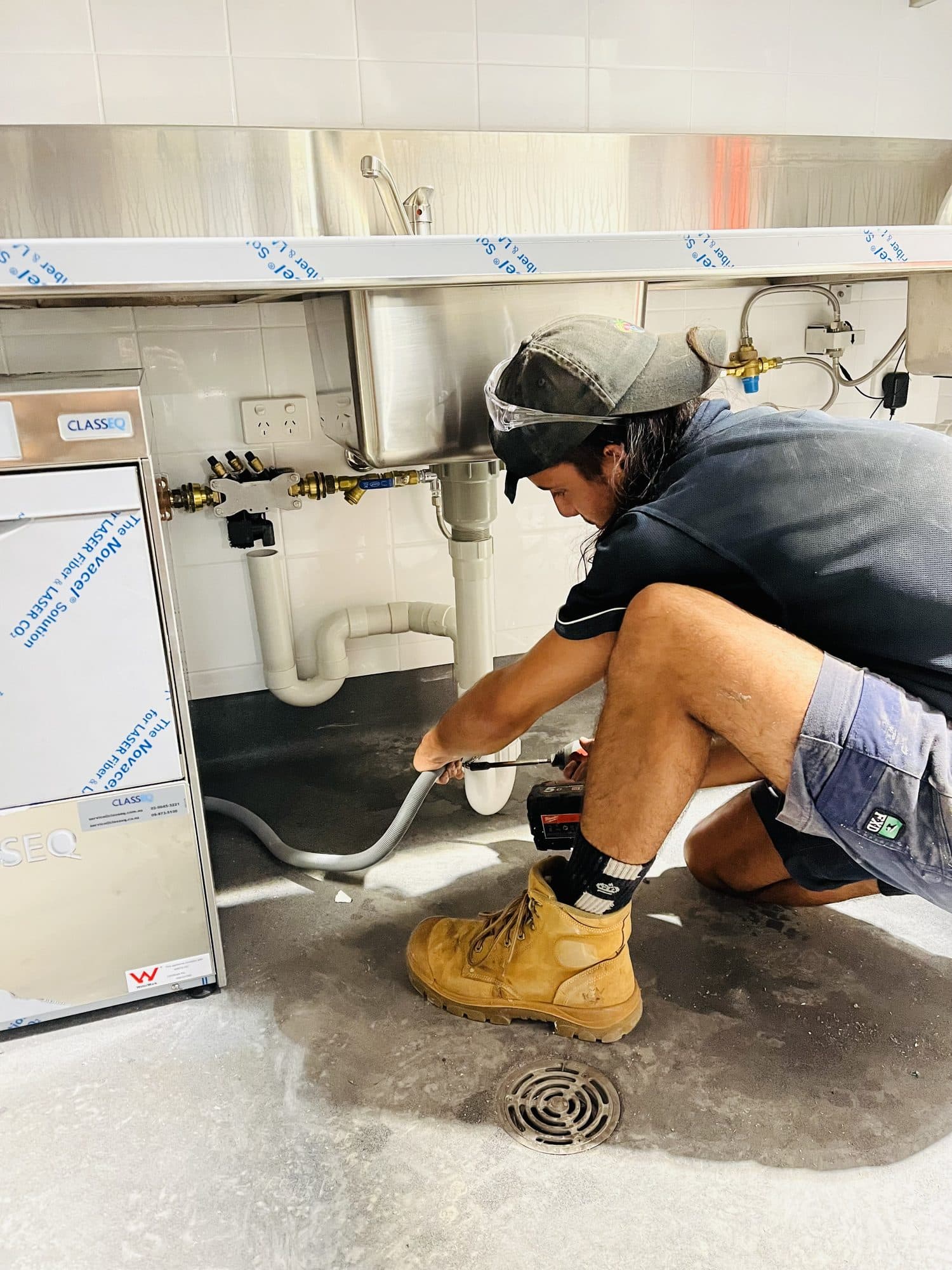 Plumbing maintenance on a stainless steel commercial sink