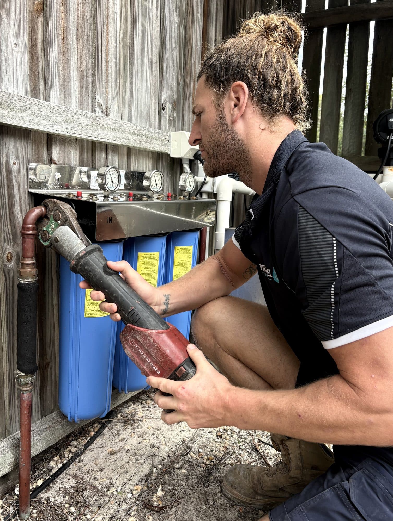 Rusty servicing a whole-house water filtration system with three cartridge canisters