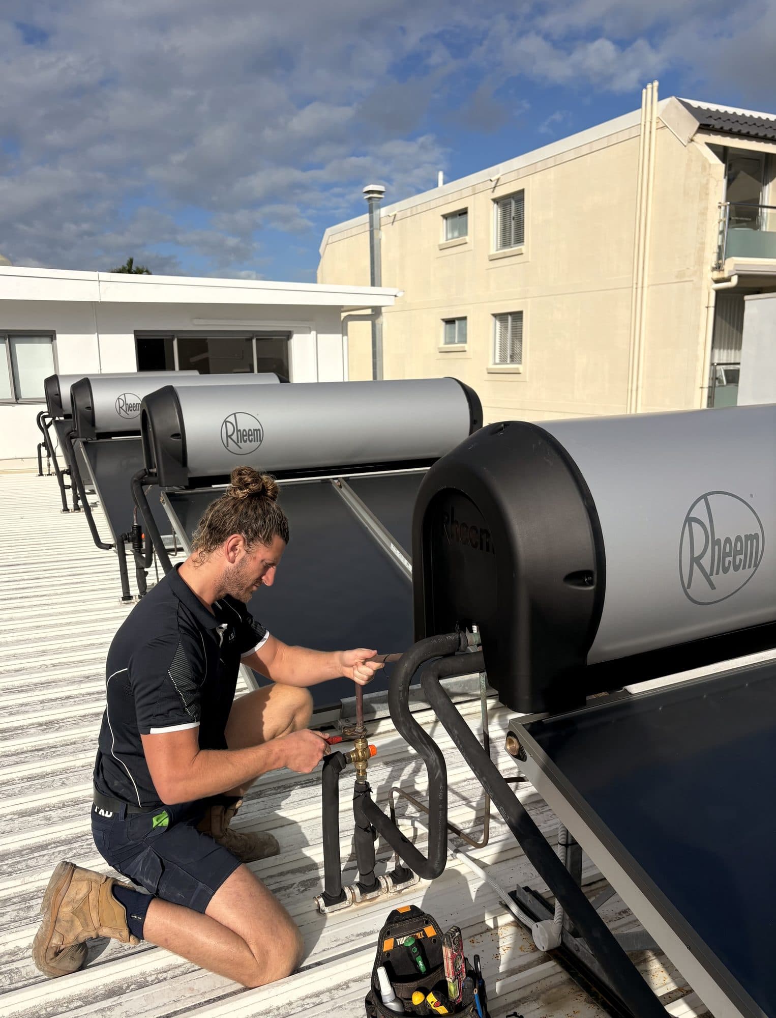 Rusty servicing a Rheem solar hot water system on a rooftop